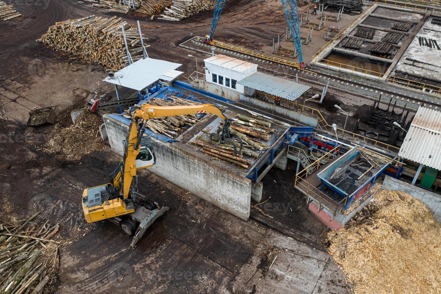 a loader loads logs at a wood processing factory from above from a drone photo
