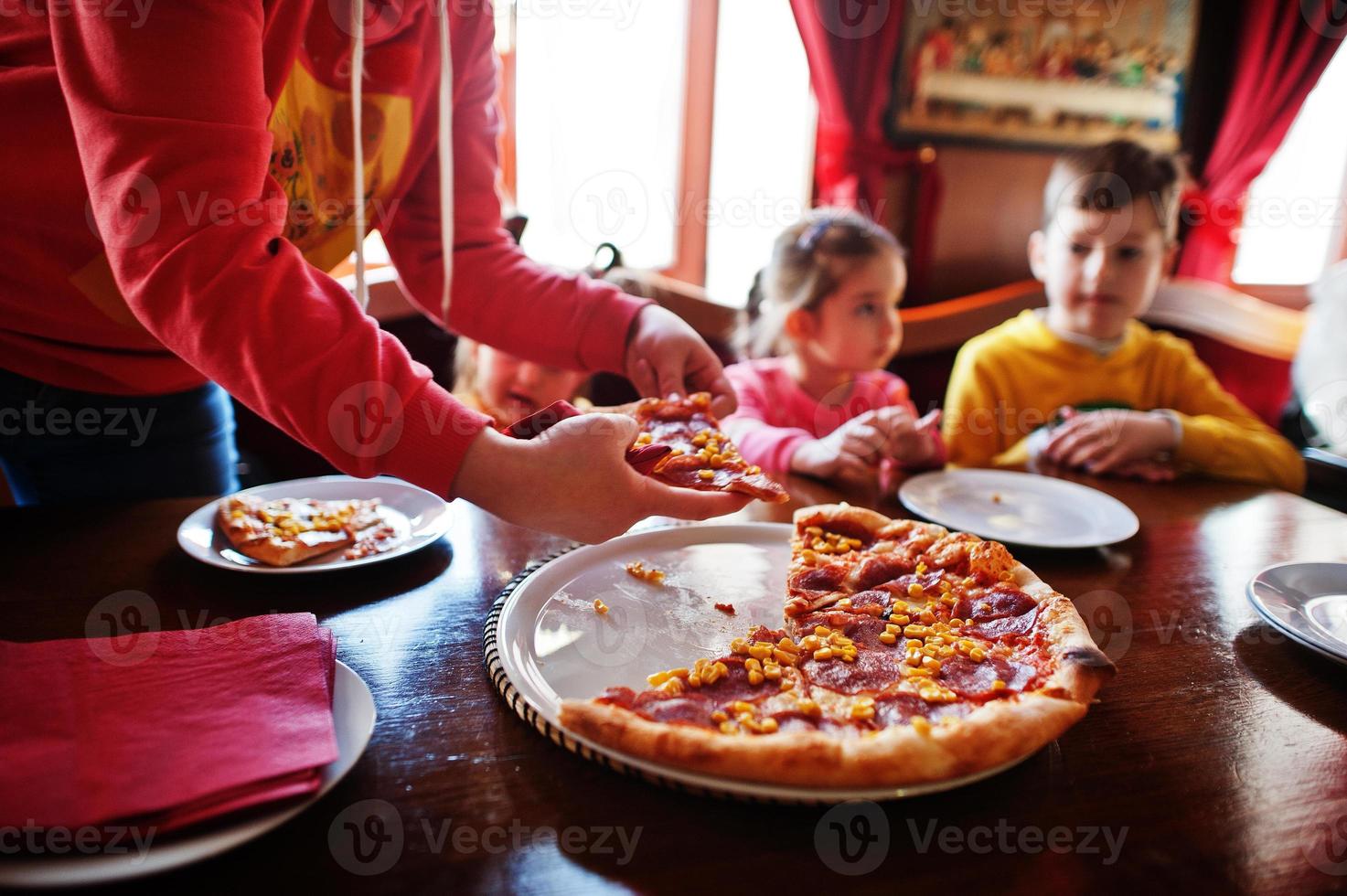 niños en cumpleaños sentados en la mesa y comiendo pizza. foto