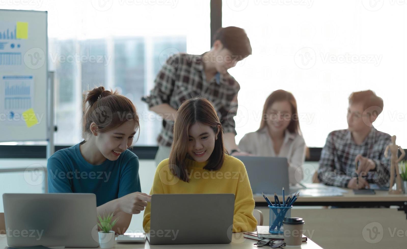 gran grupo de empresarios analizando informes de marketing en computadoras juntos. espacio de trabajo de oficina compartido abarrotado. foto