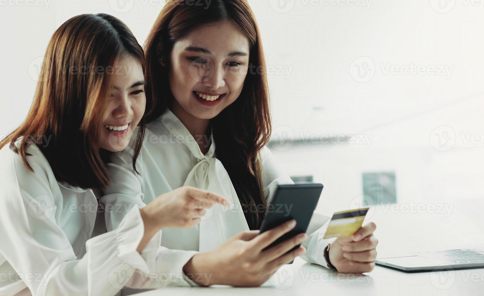 dos jóvenes asiáticas tienen tarjetas de crédito y felizmente usan sus teléfonos móviles para comprar en línea. concepto de negocio y tecnología marketing digital estilo de vida casual foto