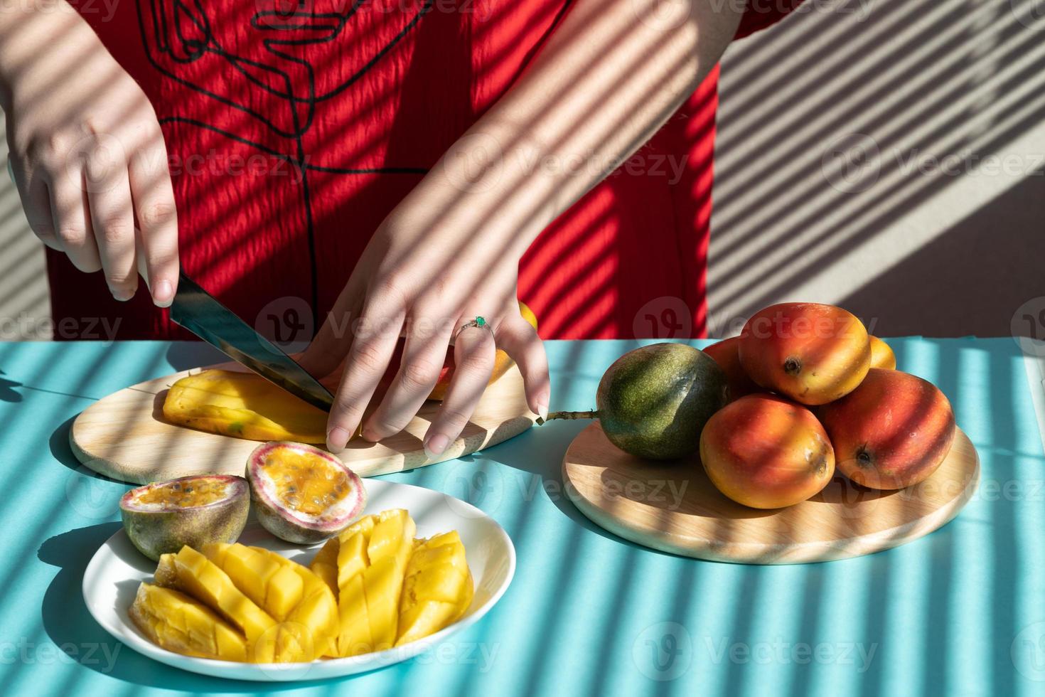 manos femeninas cortan mango y fruta de la pasión, desayuno de frutas foto