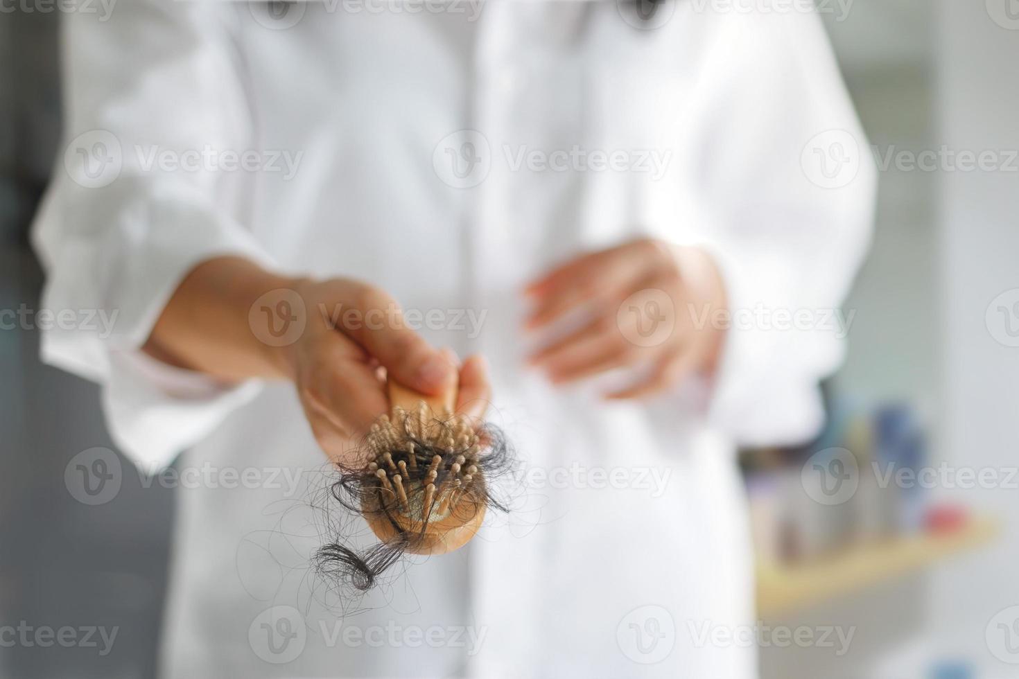 mujer perdiendo cabello en el cepillo de pelo en la mano, enfoque suave foto