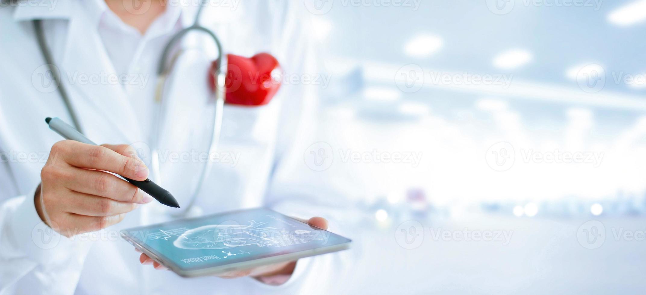 Doctor in cardiologist with stethoscope and red heart shape using tablet to analyze, diagnose for healthcare treatment photo