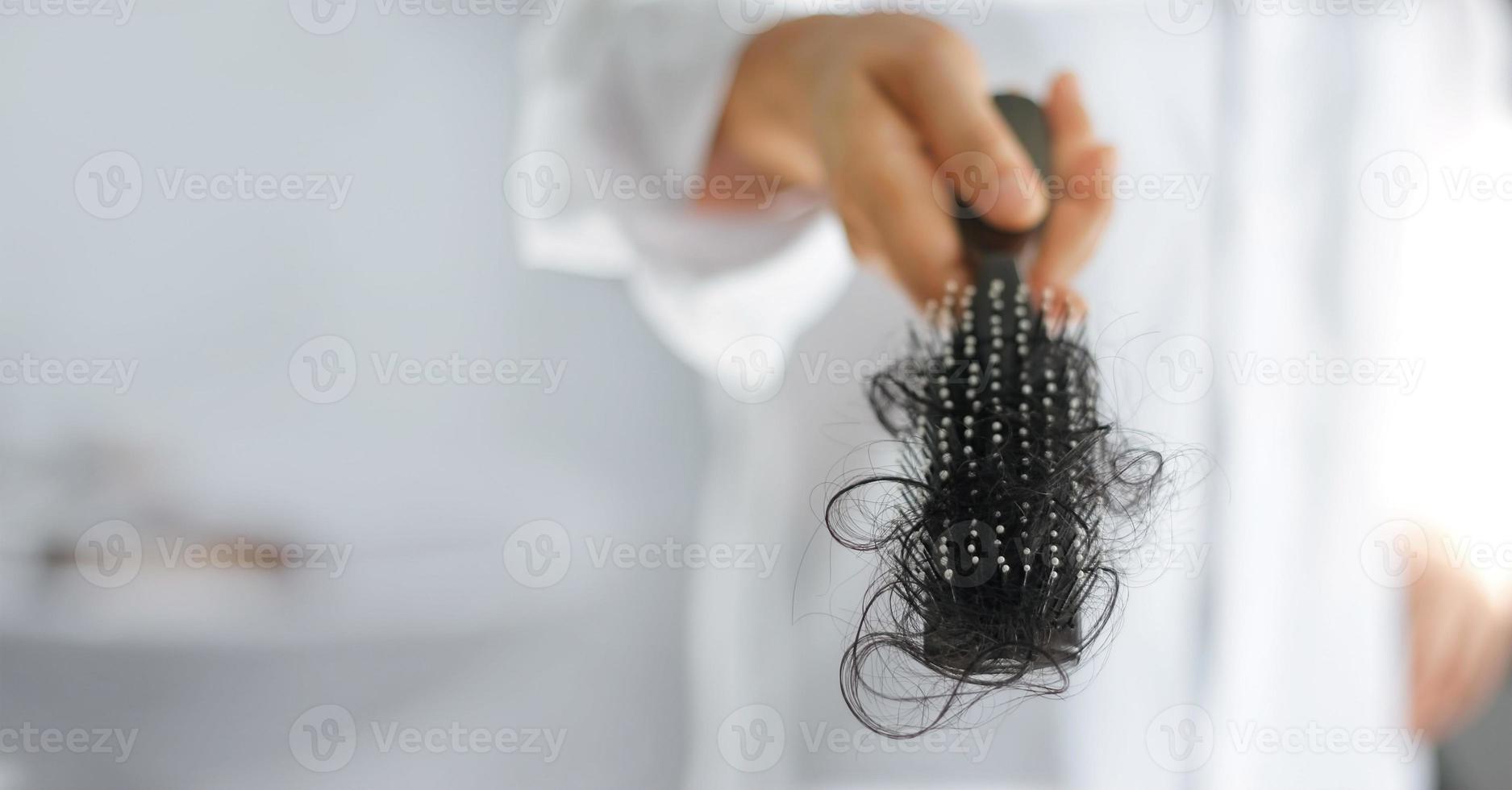 mujer perdiendo cabello en el cepillo de pelo en la mano, enfoque suave foto