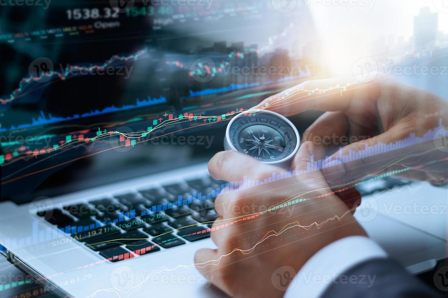 Businessman holding compass in hands, and data analyzing with using laptop stock market graph on screen, finance data and technology concept photo