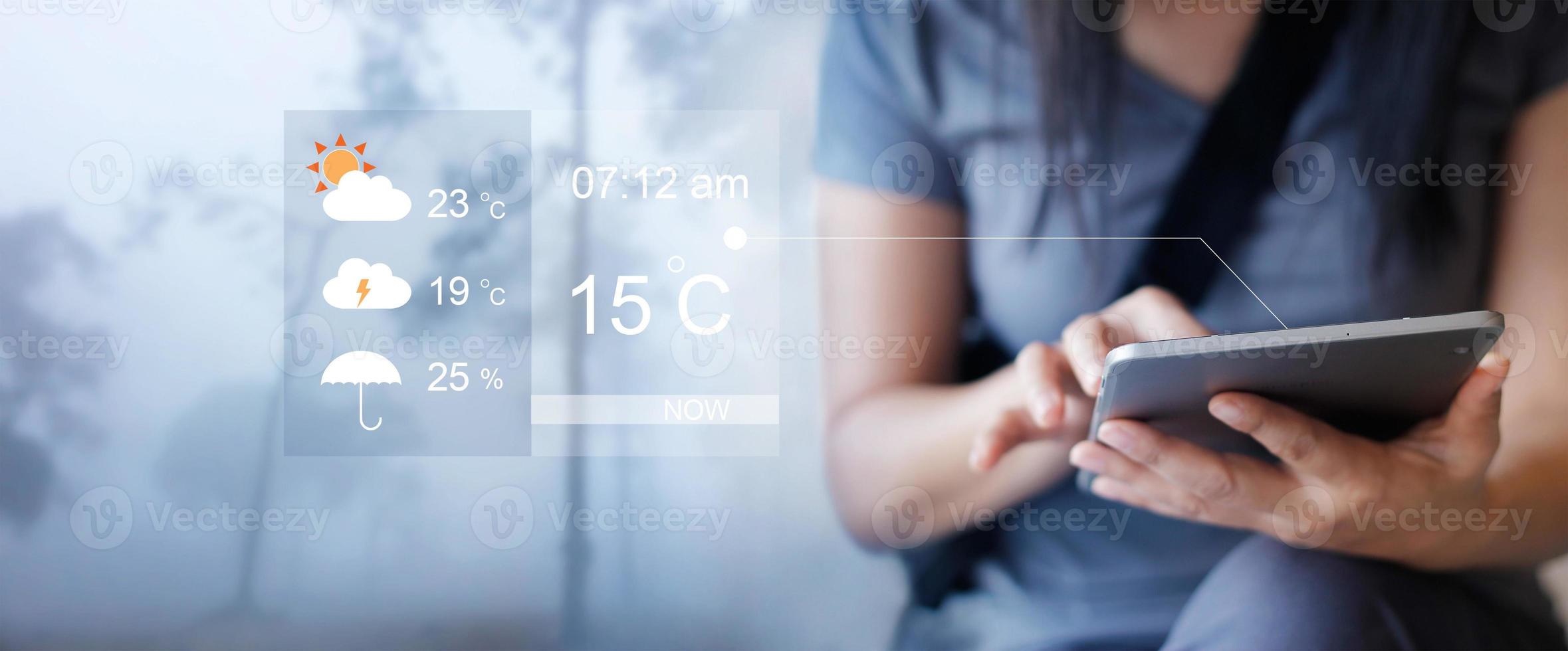 Woman checking up the weather forecast from tablet application photo