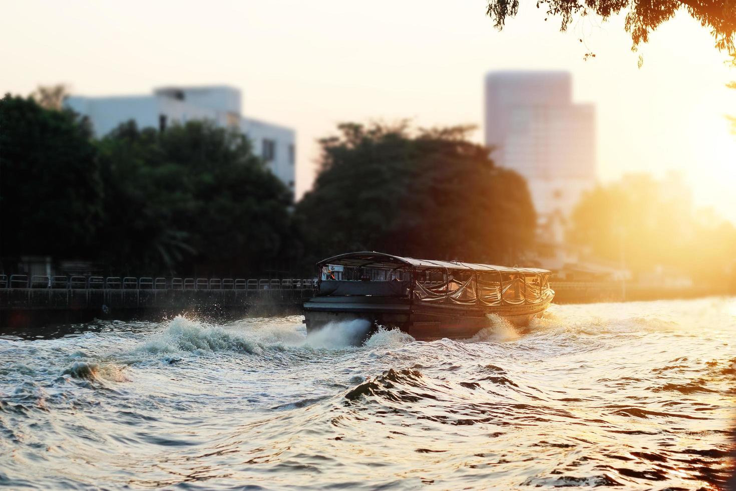 un barco tradicional en la ciudad del río sobre el fondo de la puesta de sol, tono de color dramático foto