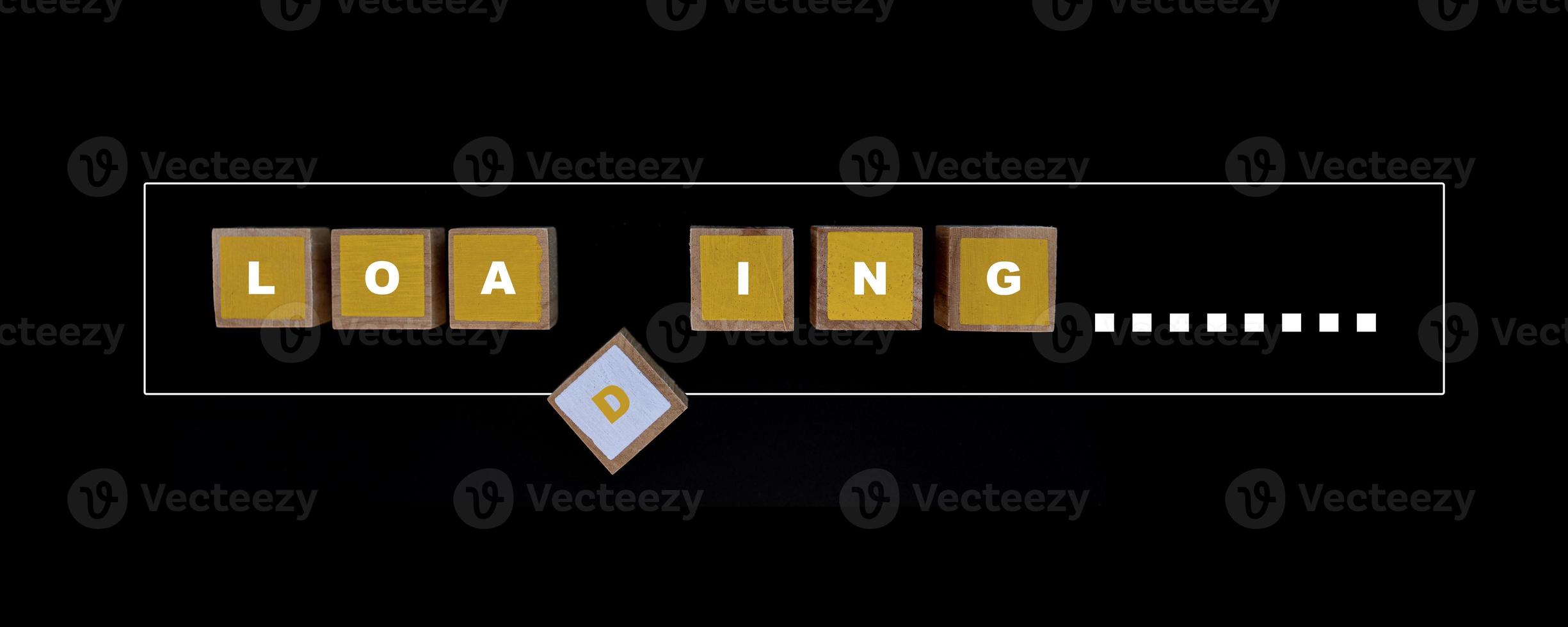 Square wood painted yellow and white color with LOADING letters in progress bar on a black background. photo