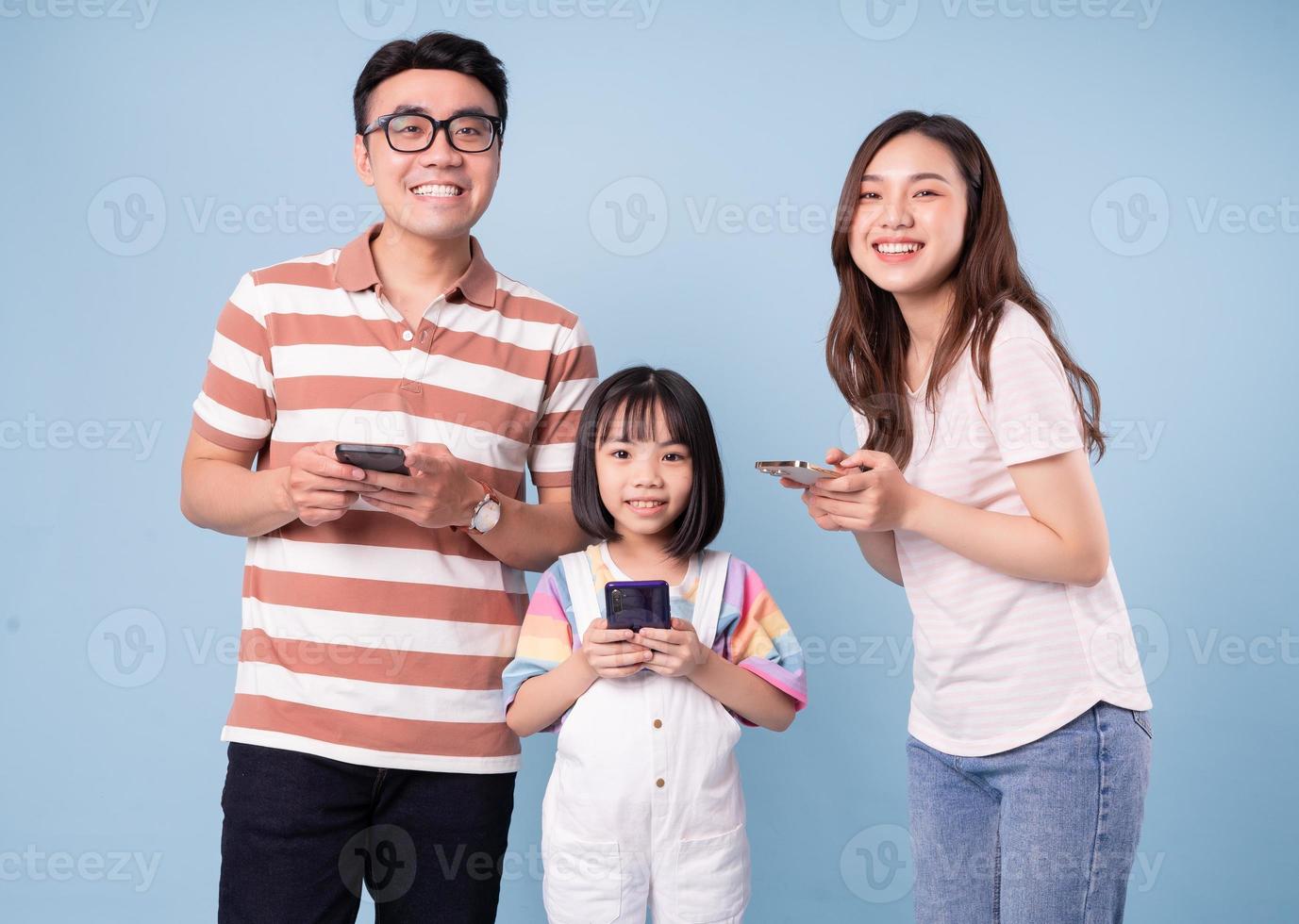 imagen de una joven familia asiática usando un teléfono inteligente con fondo azul foto