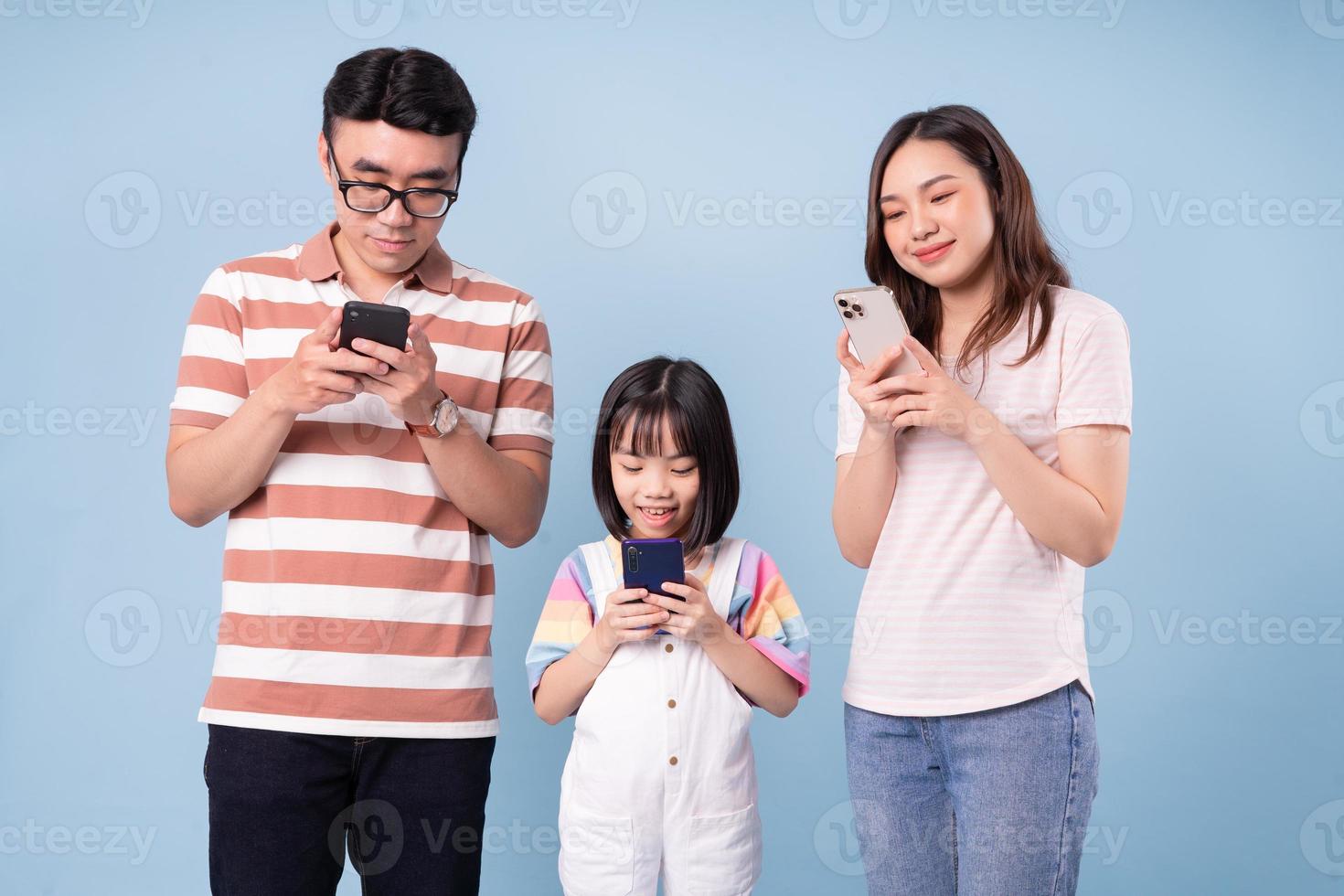 imagen de una joven familia asiática usando un teléfono inteligente con fondo azul foto