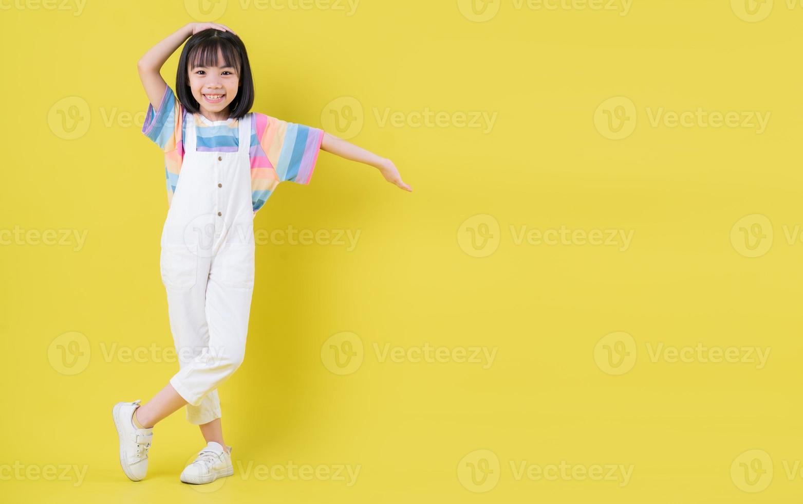 imagen completa de un niño asiático posando sobre fondo amarillo foto