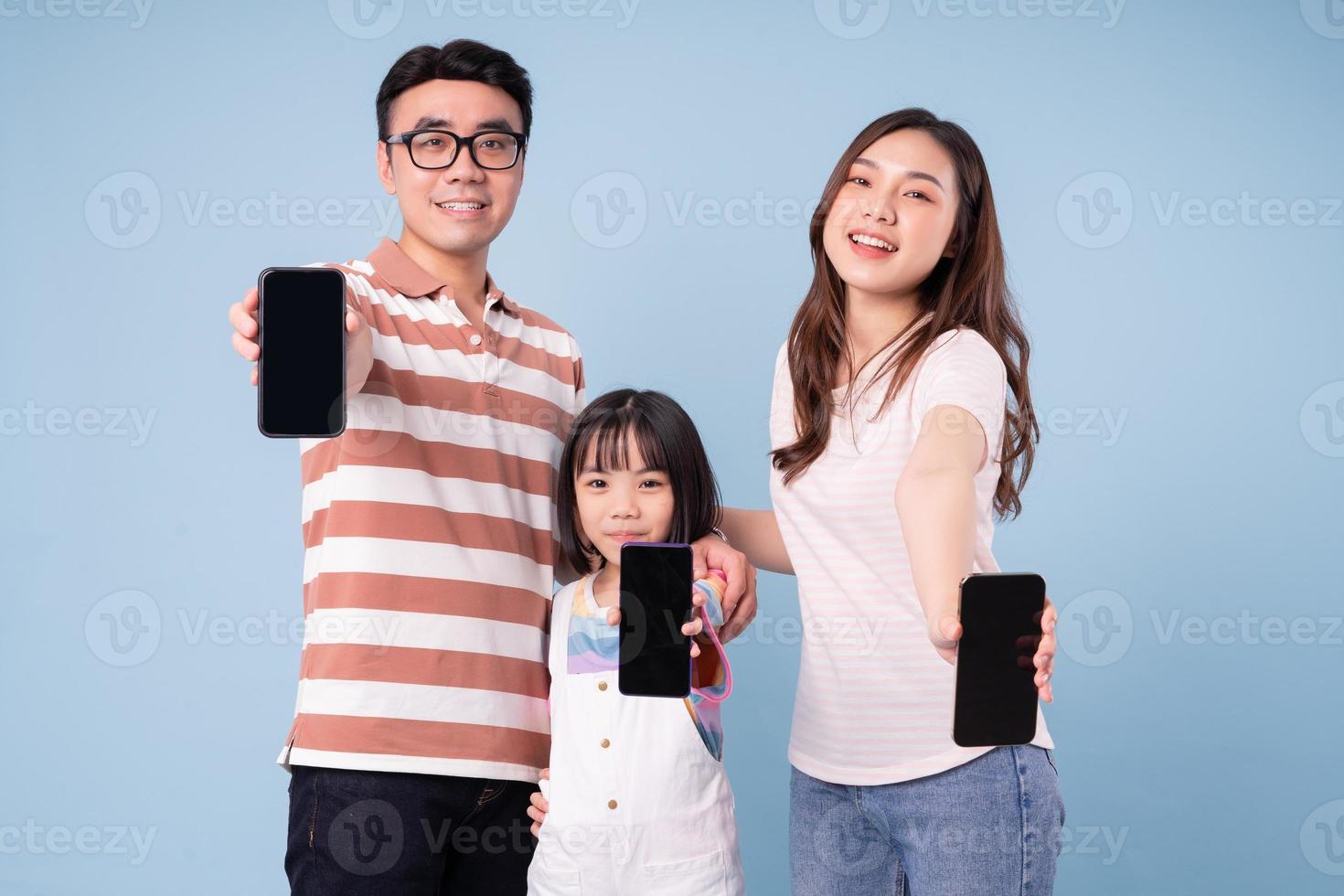 imagen de una joven familia asiática usando un teléfono inteligente con fondo azul foto
