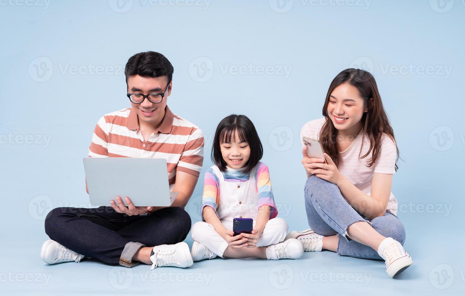 imagen de una joven familia asiática usando una laptop con fondo azul foto