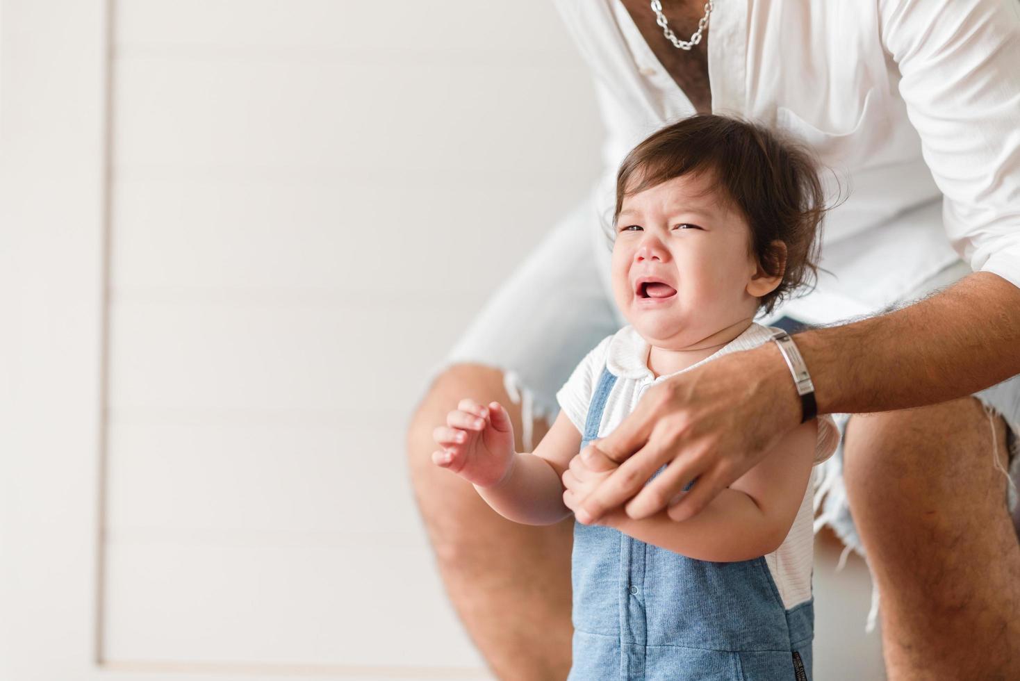 niño bebé personita está llorando en casa, recién nacido está llorando y viviendo en el interior de una casa con la familia, concepto de cuidado infantil y reconfortante foto