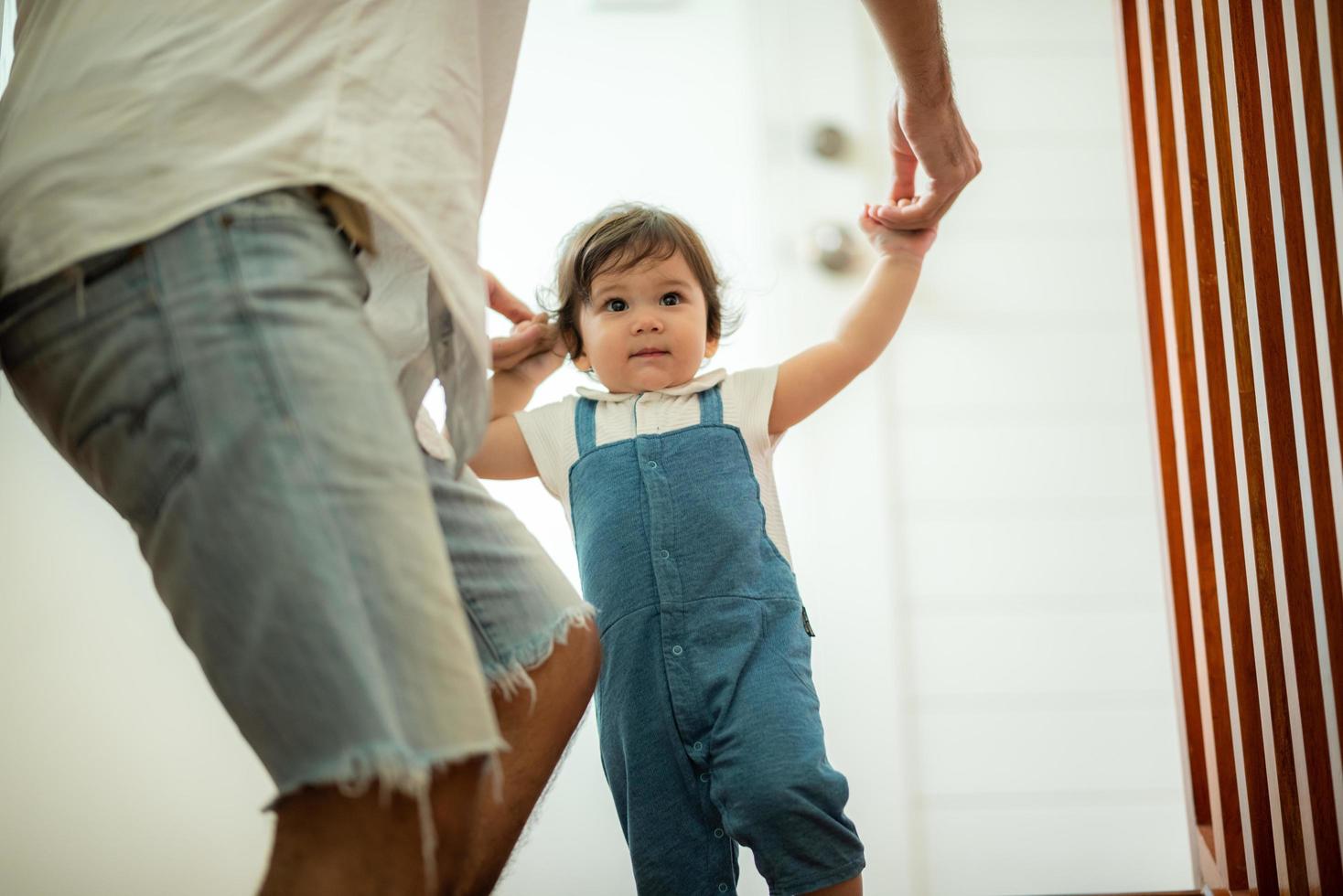 lindo concepto de familia de niño pequeño, bebé aprendiendo a caminar con el padre y la madre para ayudar a cuidar y tomar la mano, primer paso con el apoyo de los padres de la infancia, pequeño retrato de amor niño pequeño en casa foto