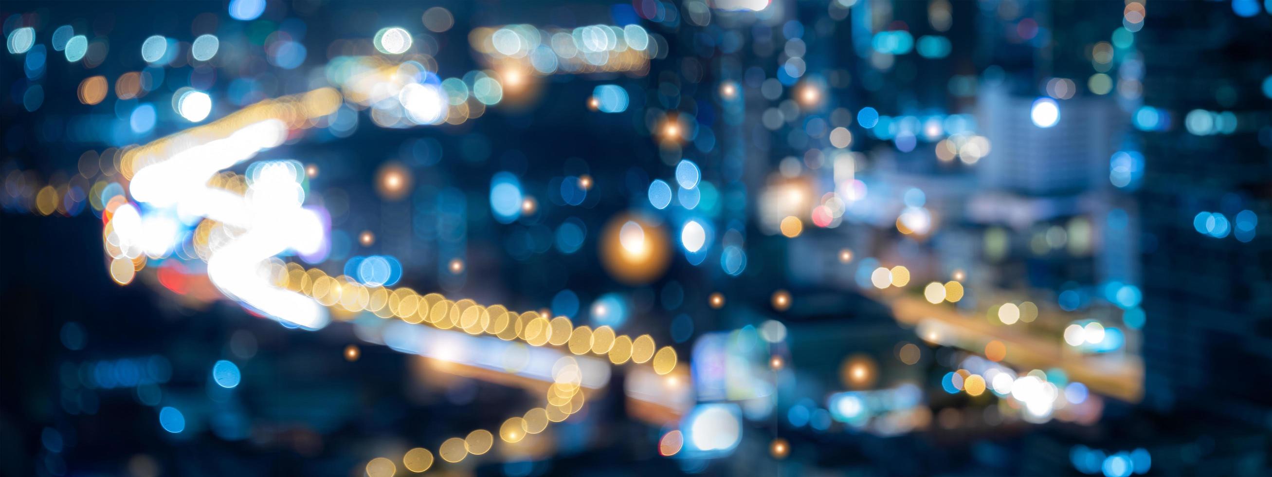 fondo borroso abstracto de la luz de la ciudad con bokeh nocturno, paisaje urbano en pancarta panorámica para usar en la pared de fondo en concepto de centro de negocios moderno, luz de camión y tráfico en la carretera foto