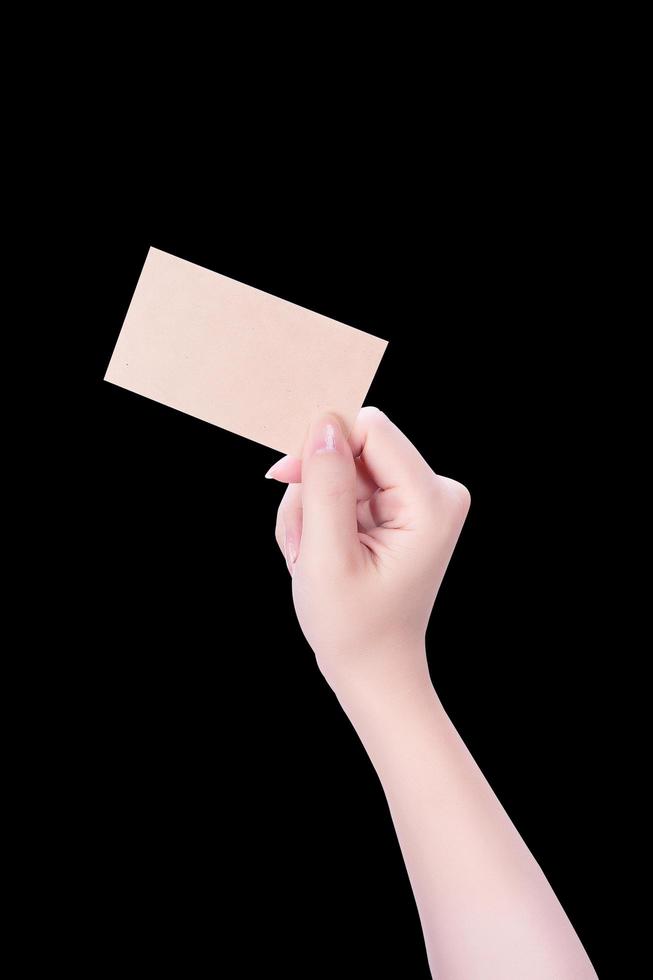 mano de niña limpia de asia joven sosteniendo una plantilla de tarjeta de papel marrón kraft en blanco aislada en fondo negro, ruta de recorte, cierre, maqueta, corte foto