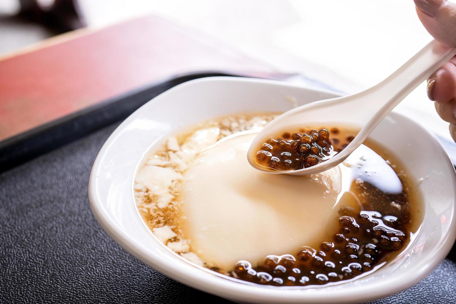Popular Taiwan gourmet - Dessert of tapioca pearl ball bubble mixed bean curd tofu pudding douhua, dou hua in white bowl, close up, lifestyle photo