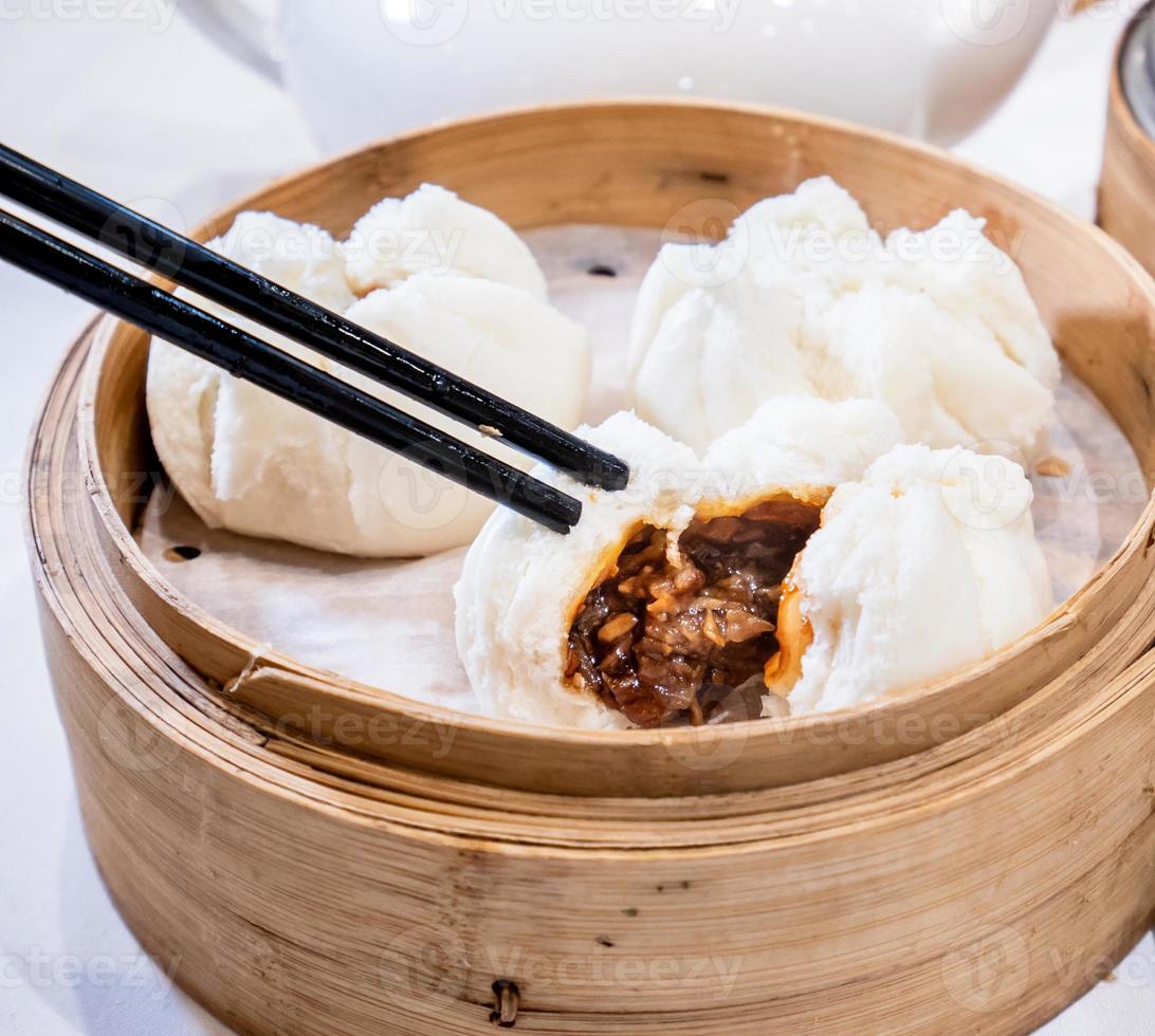 Delicious dim sum, famous cantonese food in asia - Fresh and hot Cha Siu Bao, BBQ pork bun in bamboo steamer in hong kong yumcha restaurant, close up photo