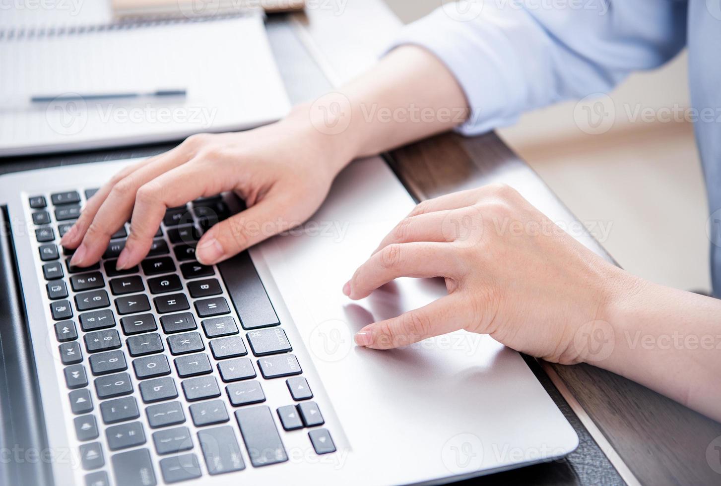 Business concept. Woman in blue shirt typing on computer with coffee on office table, backlighting, sun glare effect, close up, side view, copy space photo