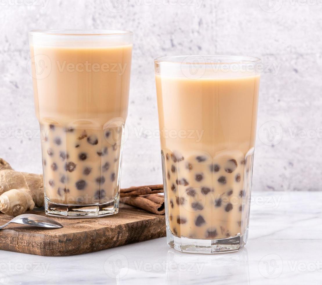 bebida popular de taiwán - té de leche de burbujas con bola de perla de tapioca en vaso de bebida sobre fondo de bandeja de madera de mesa blanca de mármol, primer plano, espacio de copia foto