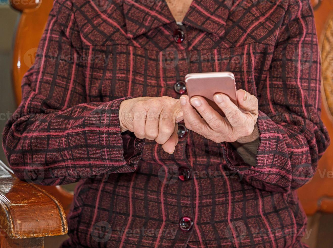 Asian elderly woman sitting and looking through something on modern smartphone, making connection with others at home, living technology, close up photo