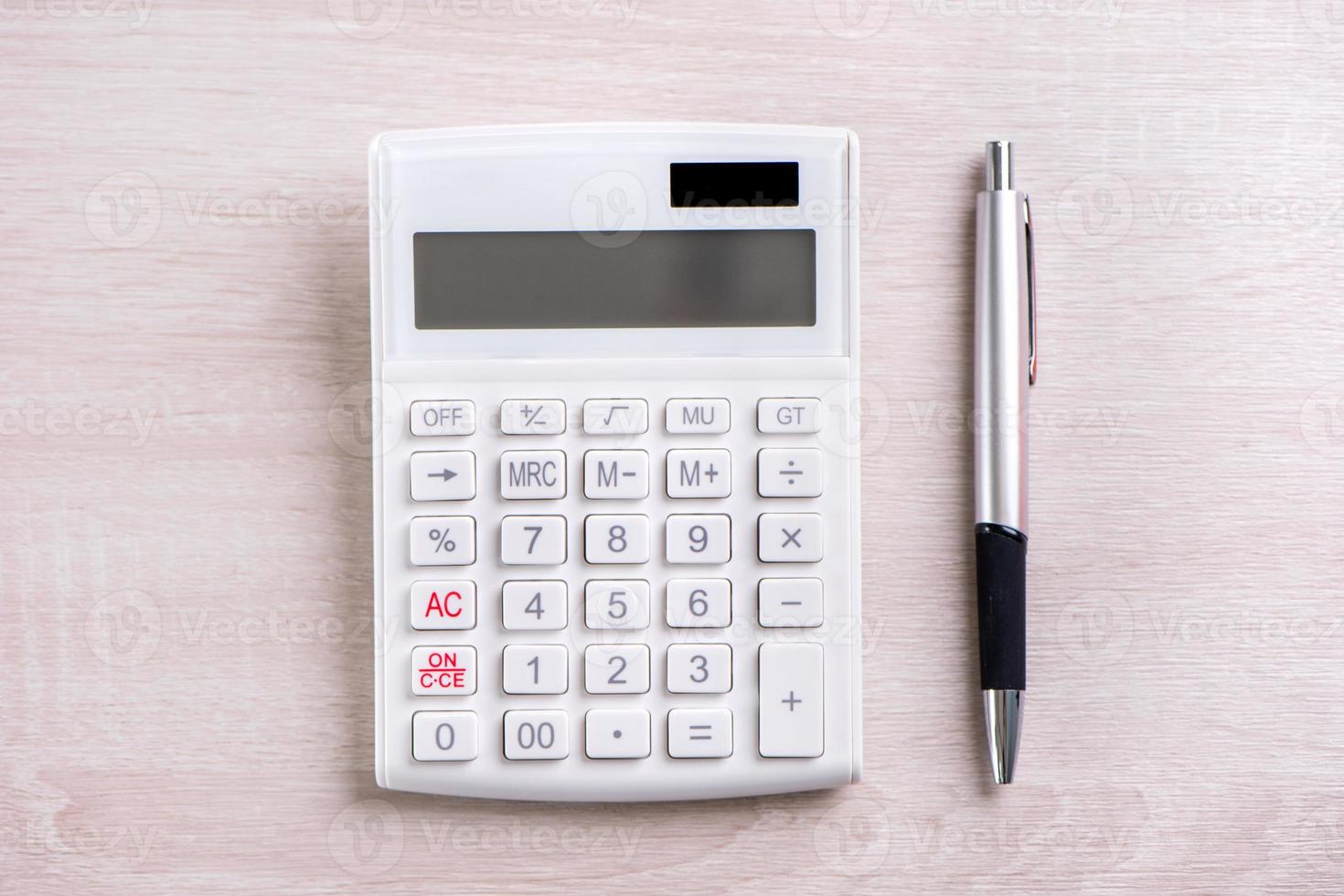 White calculator and pen on bright wooden table, analytics and statistics of financial profit, investment risk concept, copy space, top view flat lay photo