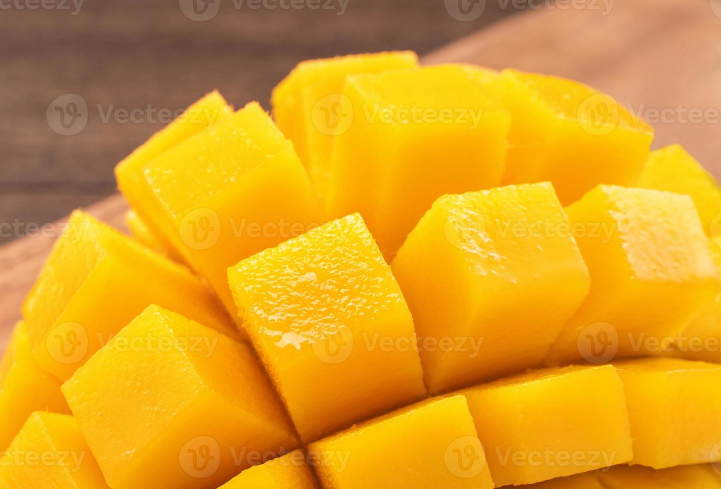 Fresh chopped mango cubes on wooden cutting board and rustic timber background. Tropical summer fruit concept, close up, macro, copy space. photo