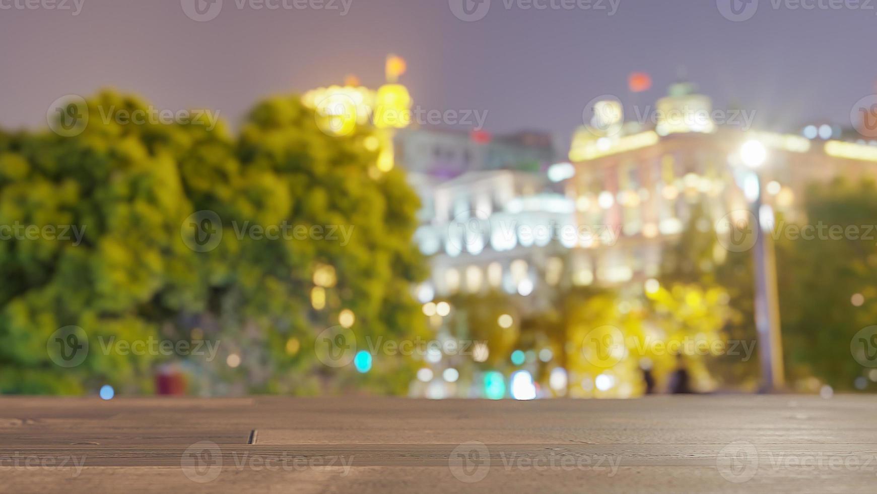 mesa de madera sobre edificios borrosos en el fondo de la ciudad nocturna. para exhibición de productos de montaje o diseño visual clave. foto