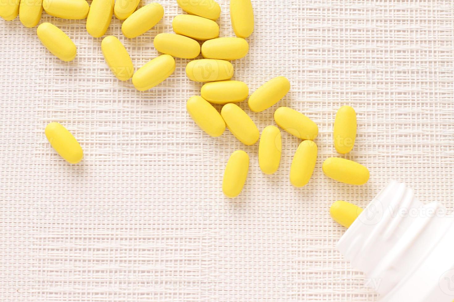 Yellow pills vitamins, bunch of tablets on white table photo