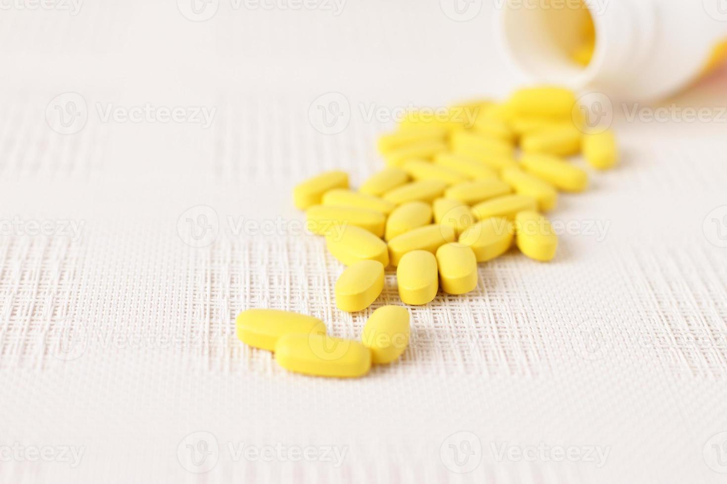 Yellow pills vitamins, bunch of tablets on white table photo