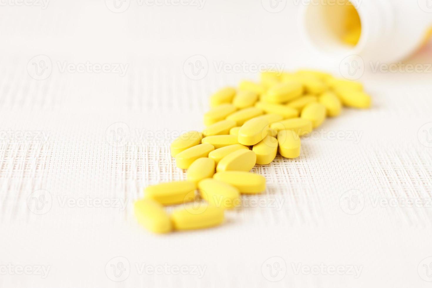 Yellow pills vitamins, bunch of tablets on white table photo