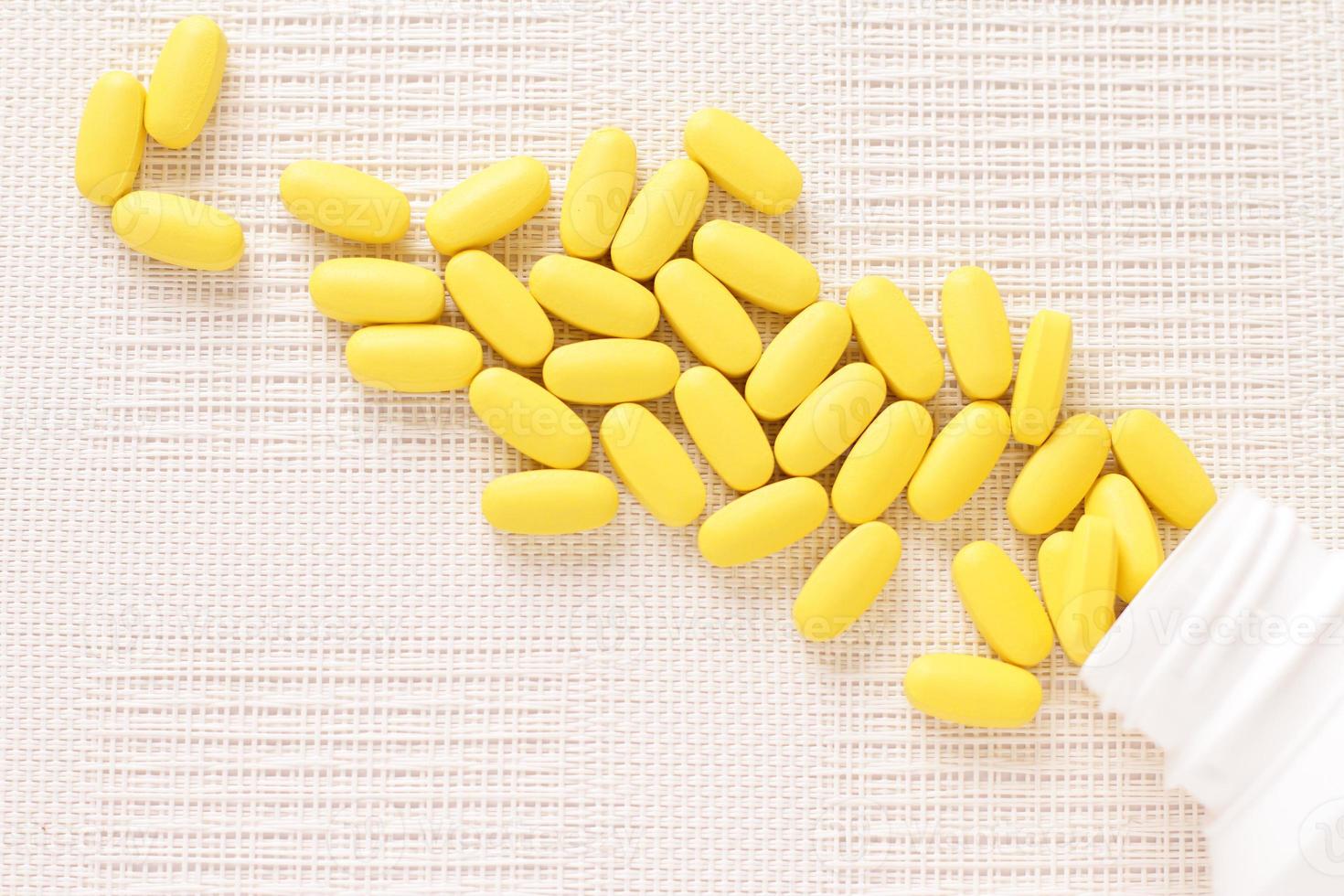 Yellow pills vitamins, bunch of tablets on white table photo