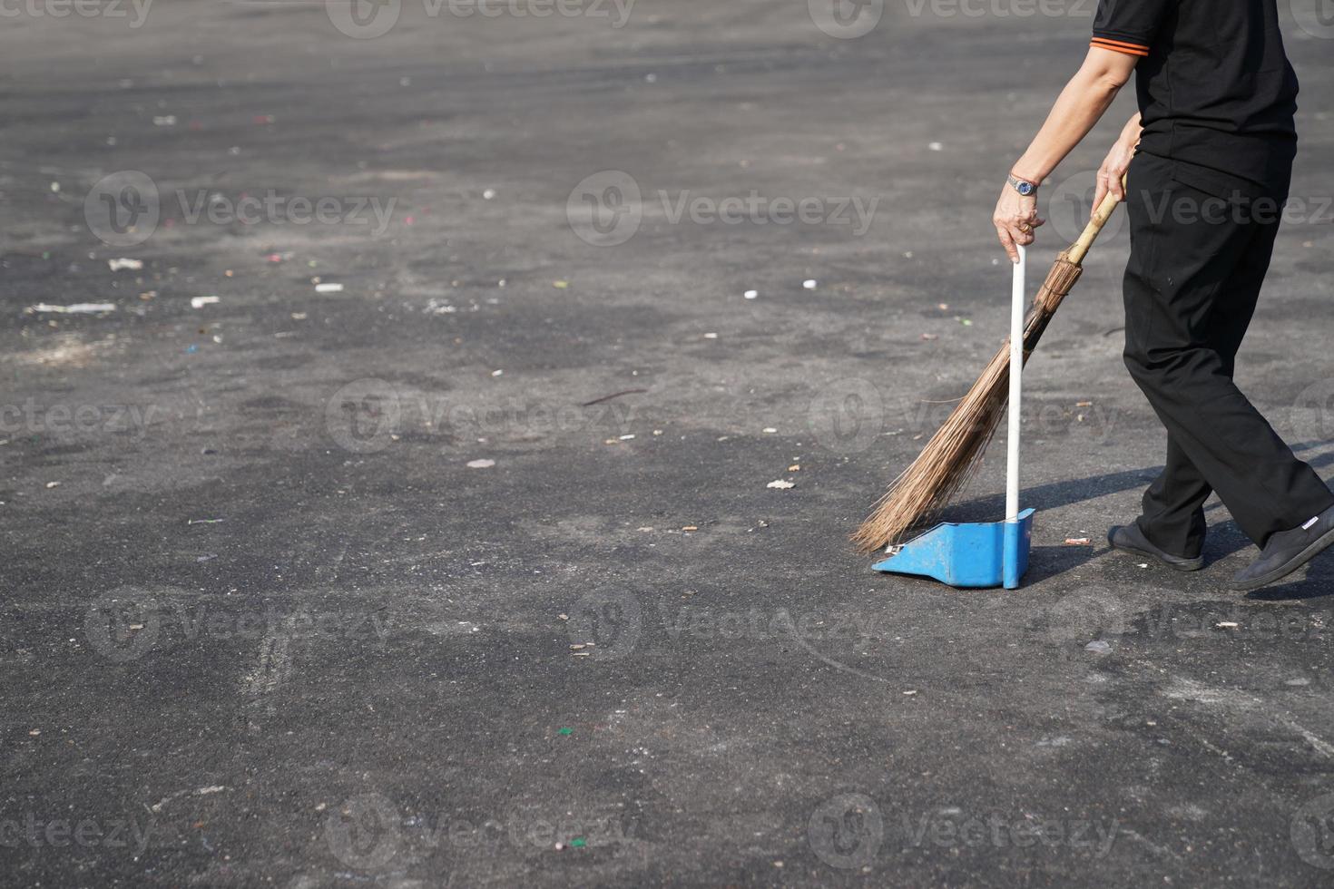 cleaner sweep trash in large asphalt outdoor area at noon. photo