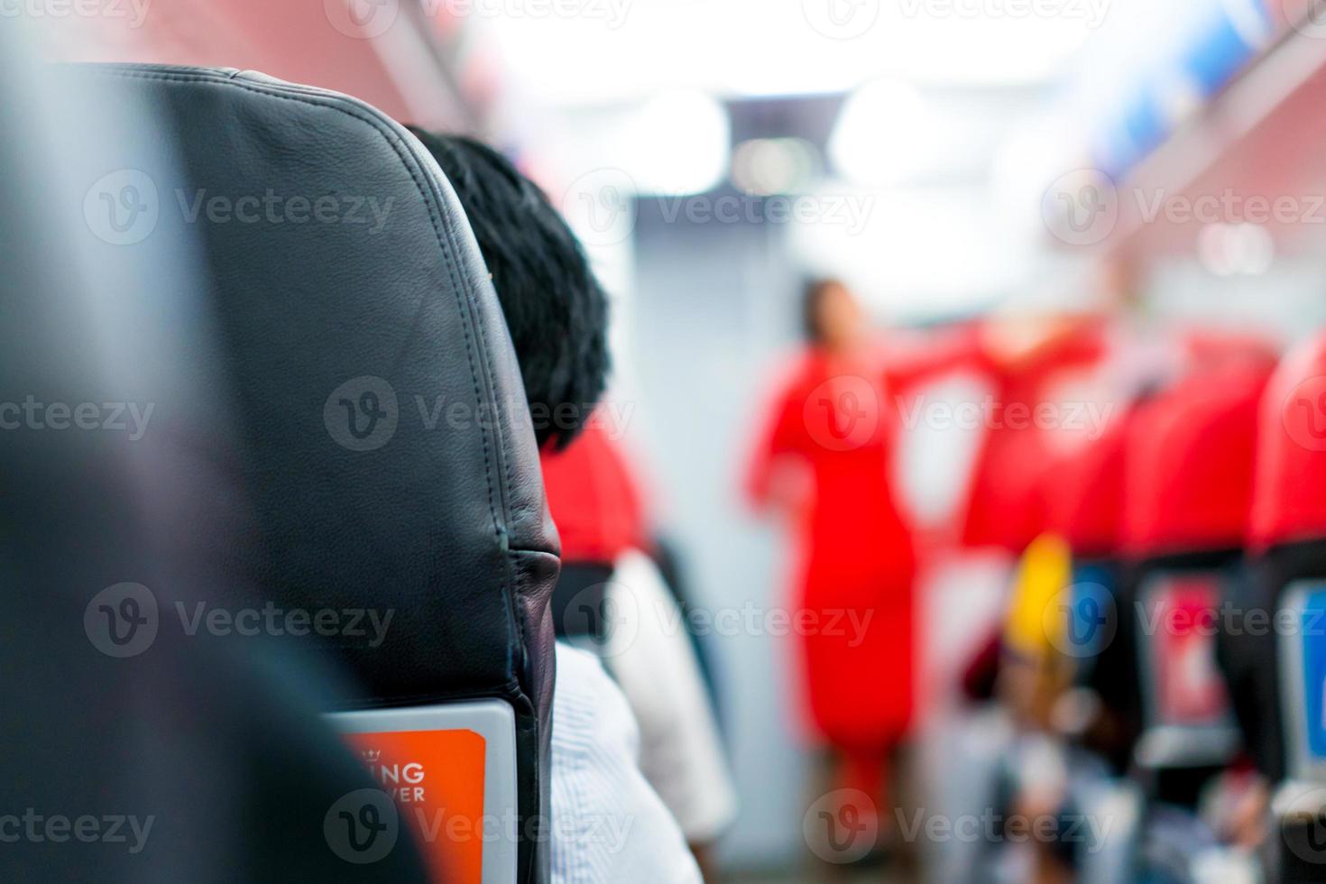 men in plane seat looks at the airhostess explain at the front of the row. photo