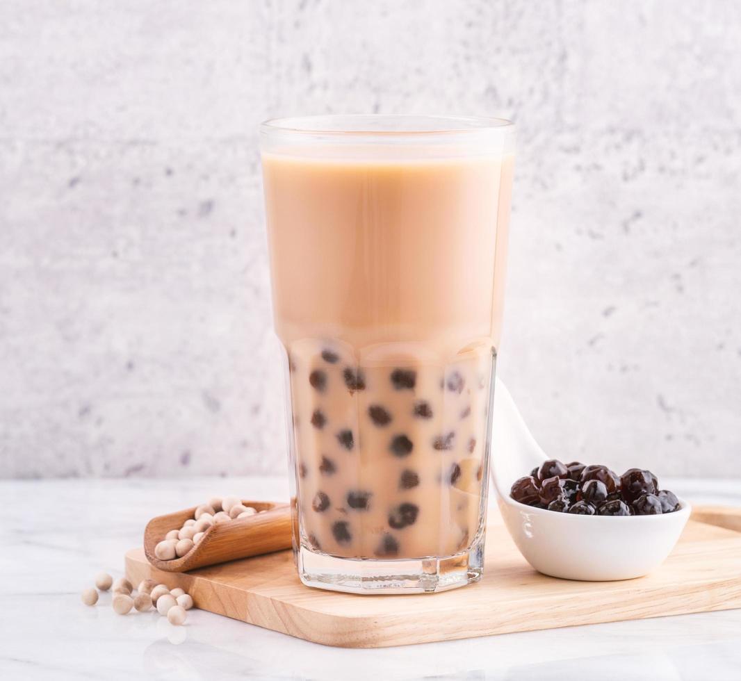 bebida popular de taiwán - té de leche de burbujas con bola de perla de tapioca en vaso de bebida sobre fondo de bandeja de madera de mesa blanca de mármol, primer plano, espacio de copia foto