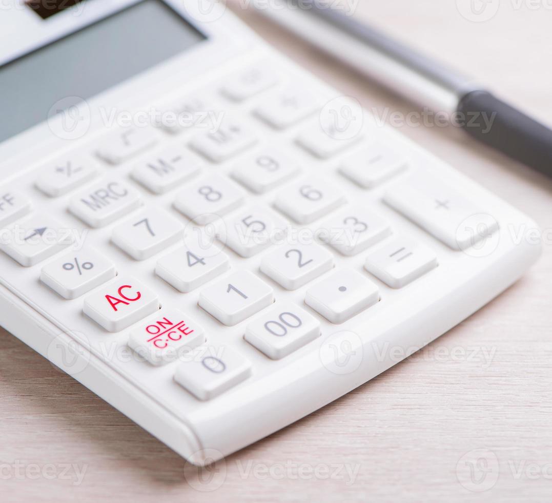 White calculator and pen on bright wooden table, analytics and statistics of financial profit, investment risk concept, copy space, macro, close up photo
