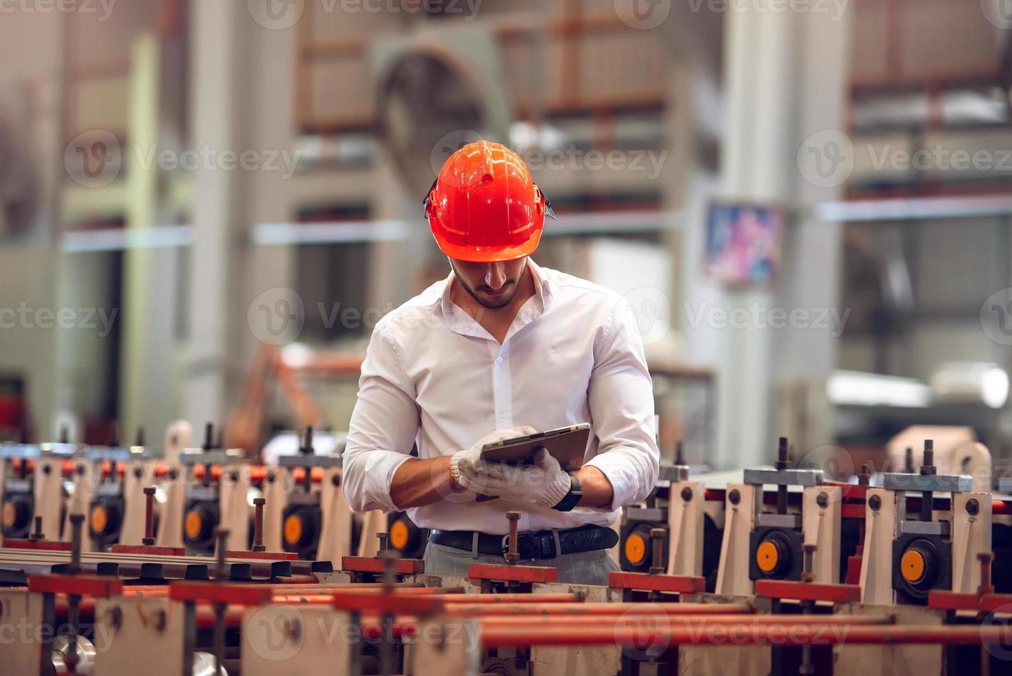 trabajador de fábrica revisando el proceso de la máquina eléctrica en el lugar de trabajo industrial, usando sombrero duro por seguridad foto