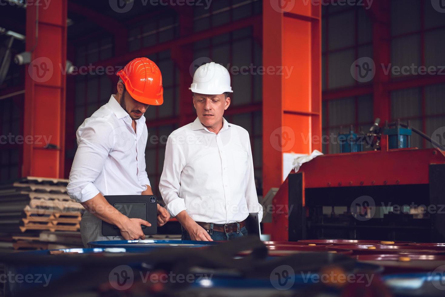 Factory worker foreman and engineer manager working together at industrial worksite , wearing hard hat for safety photo