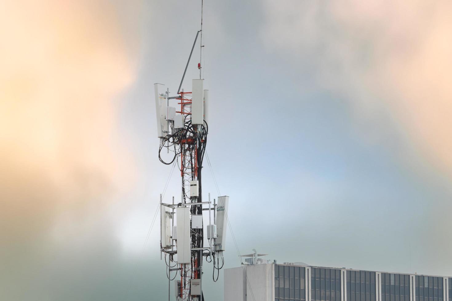 Telecommunication tower near building. Antenna. Radio and satellite pole on gray sky. Communication technology. Telecommunication industry. Mobile or telecom 4g network. Telecommunication industry. photo