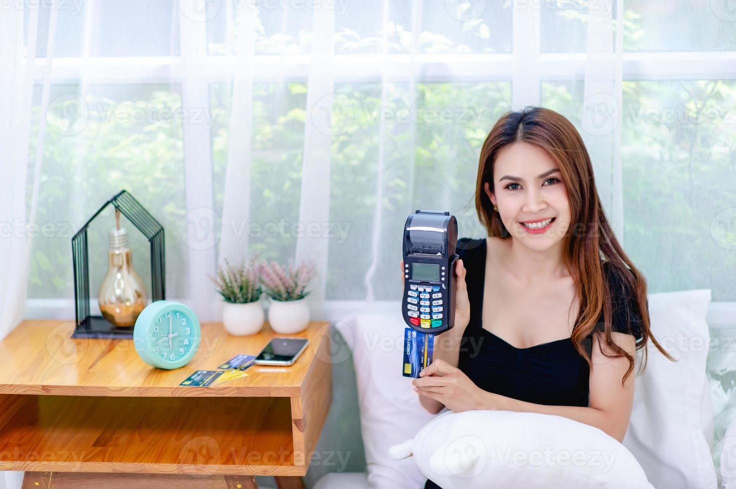 Woman and credit card With a credit card swipe machine in the bed, the concept of running an online business all the time photo
