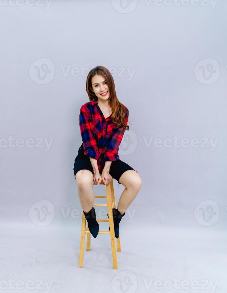 The young woman sitting on the chair smiled happily with the photo shoot. Concept