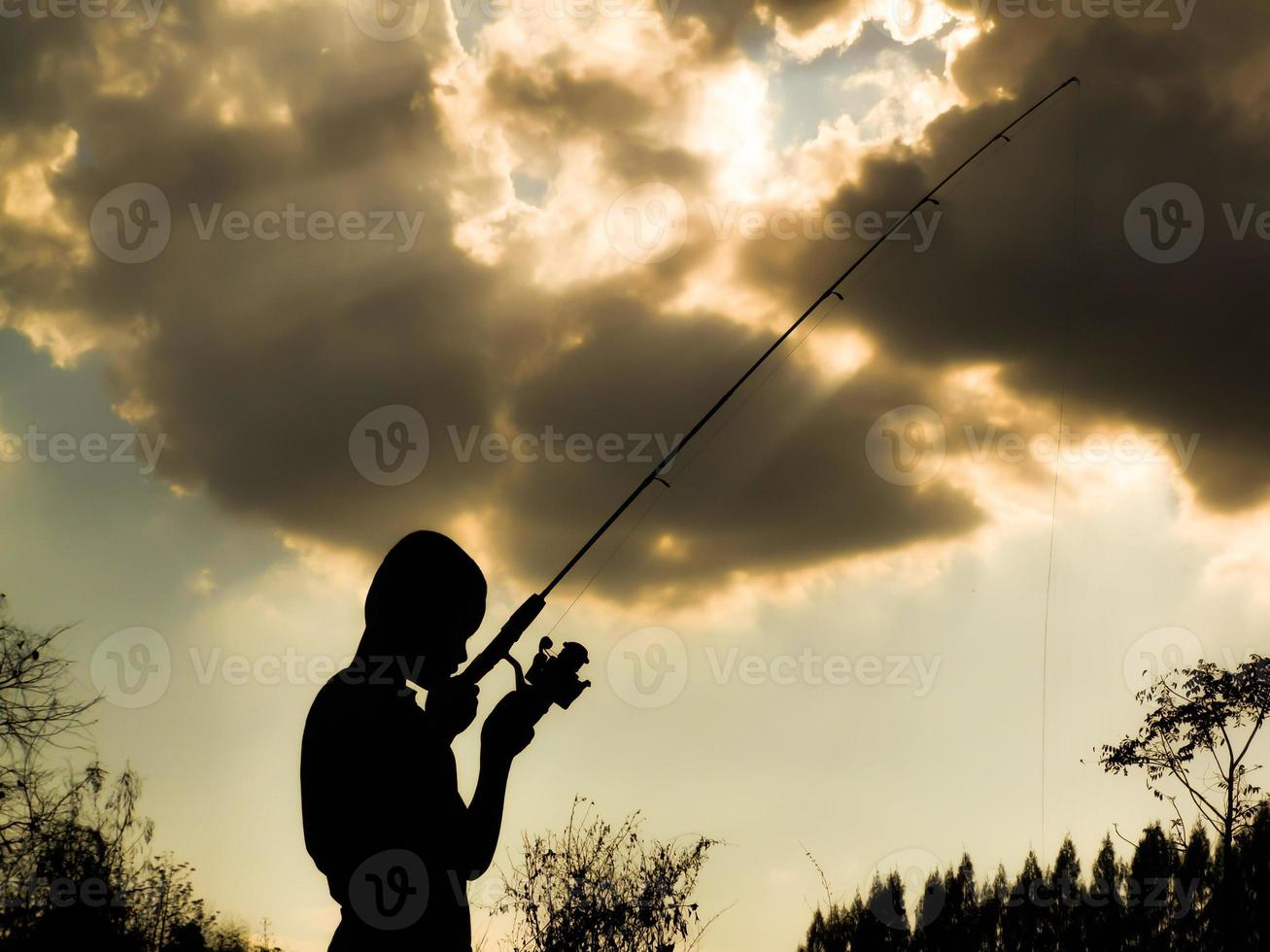 silhouette of a child fishing Children's happy time in the midst of nature at sunset photo