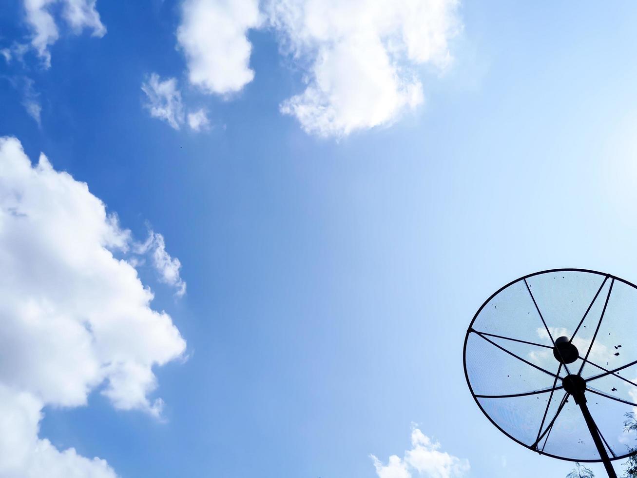 A picture of a cloudy daytime sky and a home TV satellite dish. photo