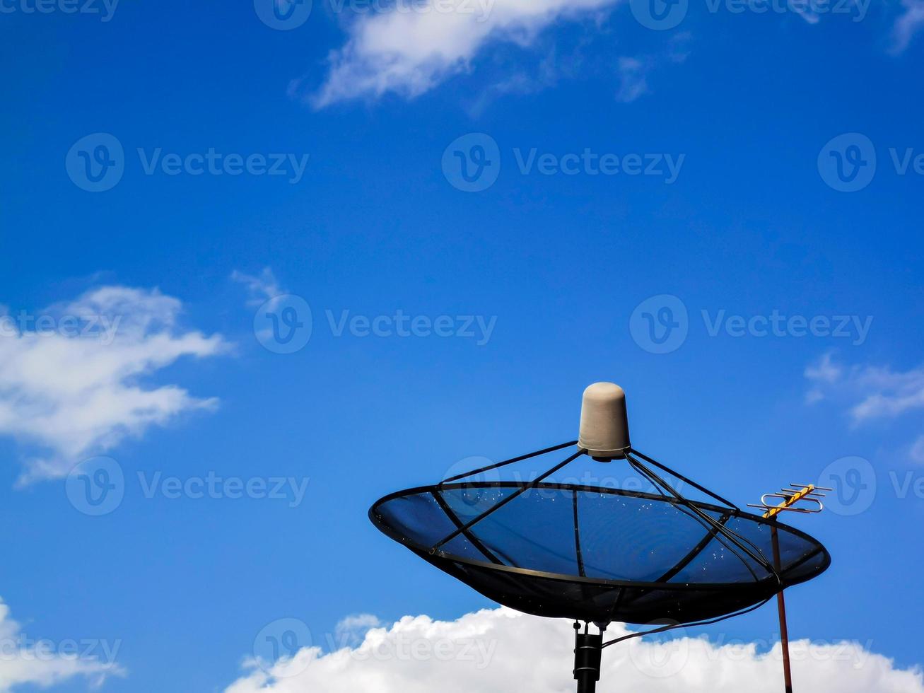 A picture of a cloudy daytime sky and a home TV satellite dish. photo