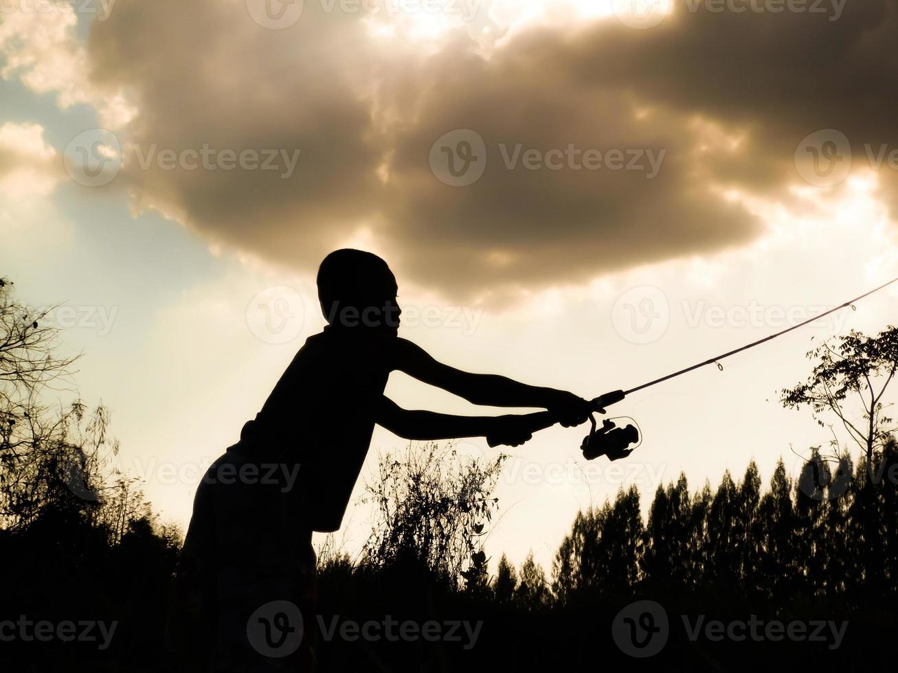 silhouette of a child fishing Children's happy time in the midst of nature at sunset photo