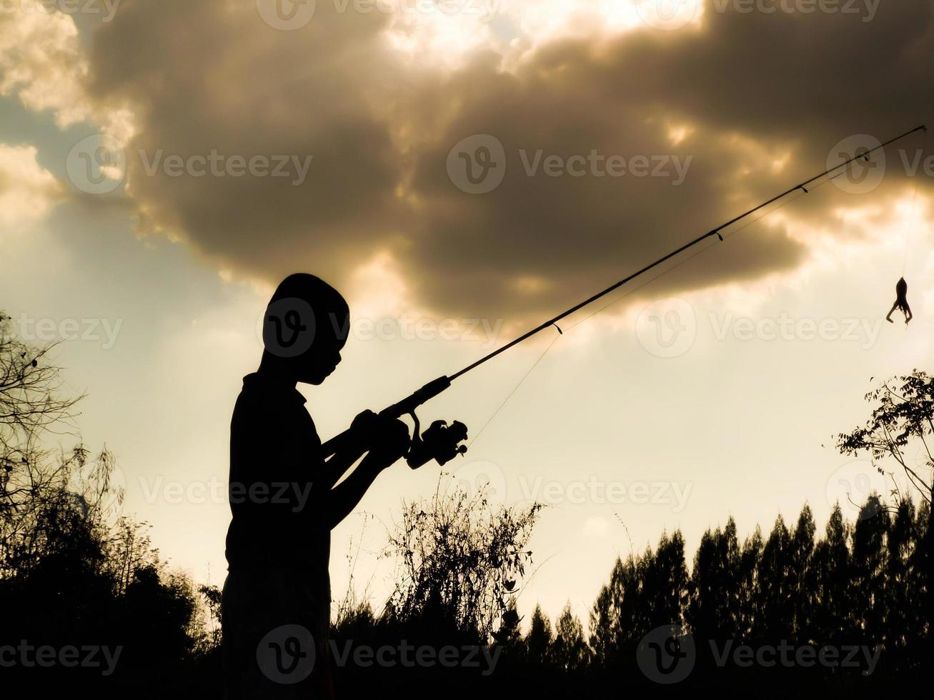 silueta de un niño pescando el tiempo feliz de los niños en medio de la naturaleza al atardecer foto