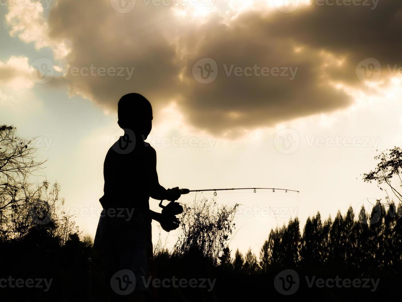 silhouette of a child fishing Children's happy time in the midst of nature at sunset photo