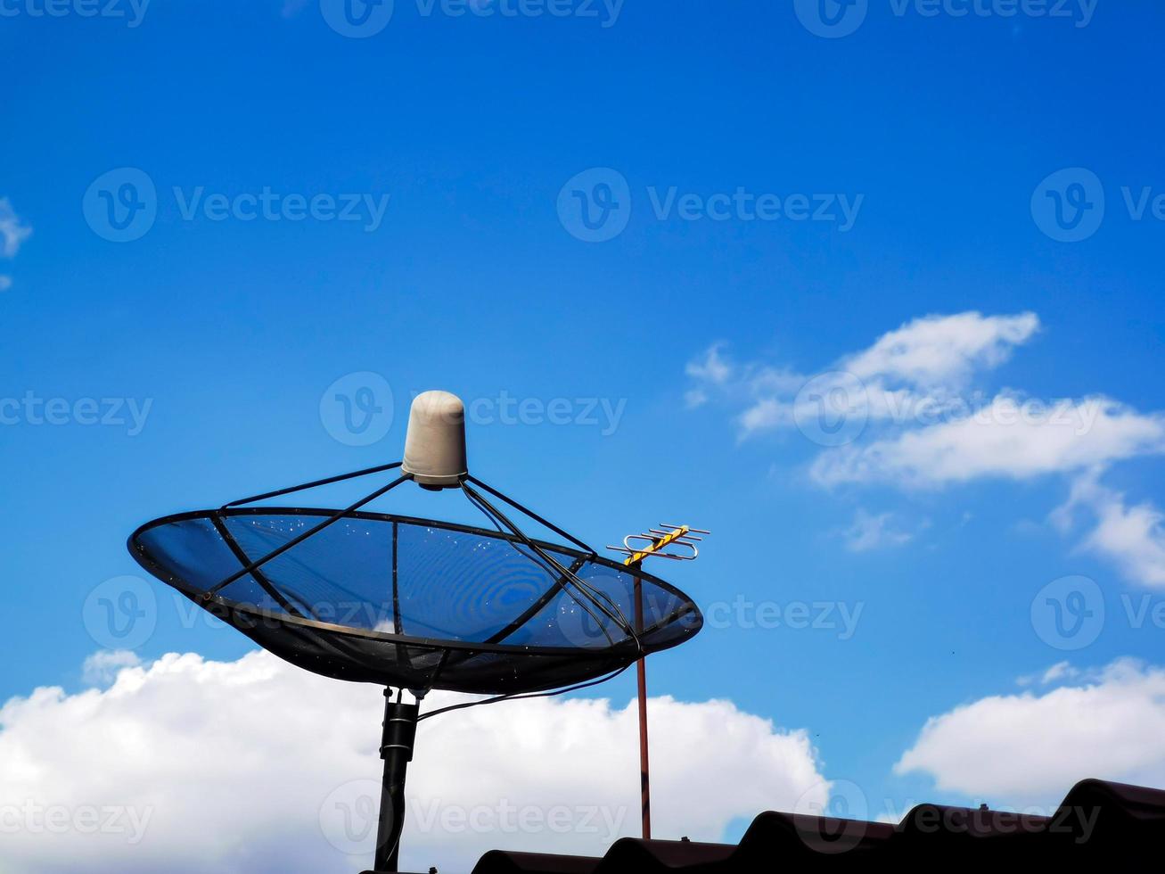 A picture of a cloudy daytime sky and a home TV satellite dish. photo