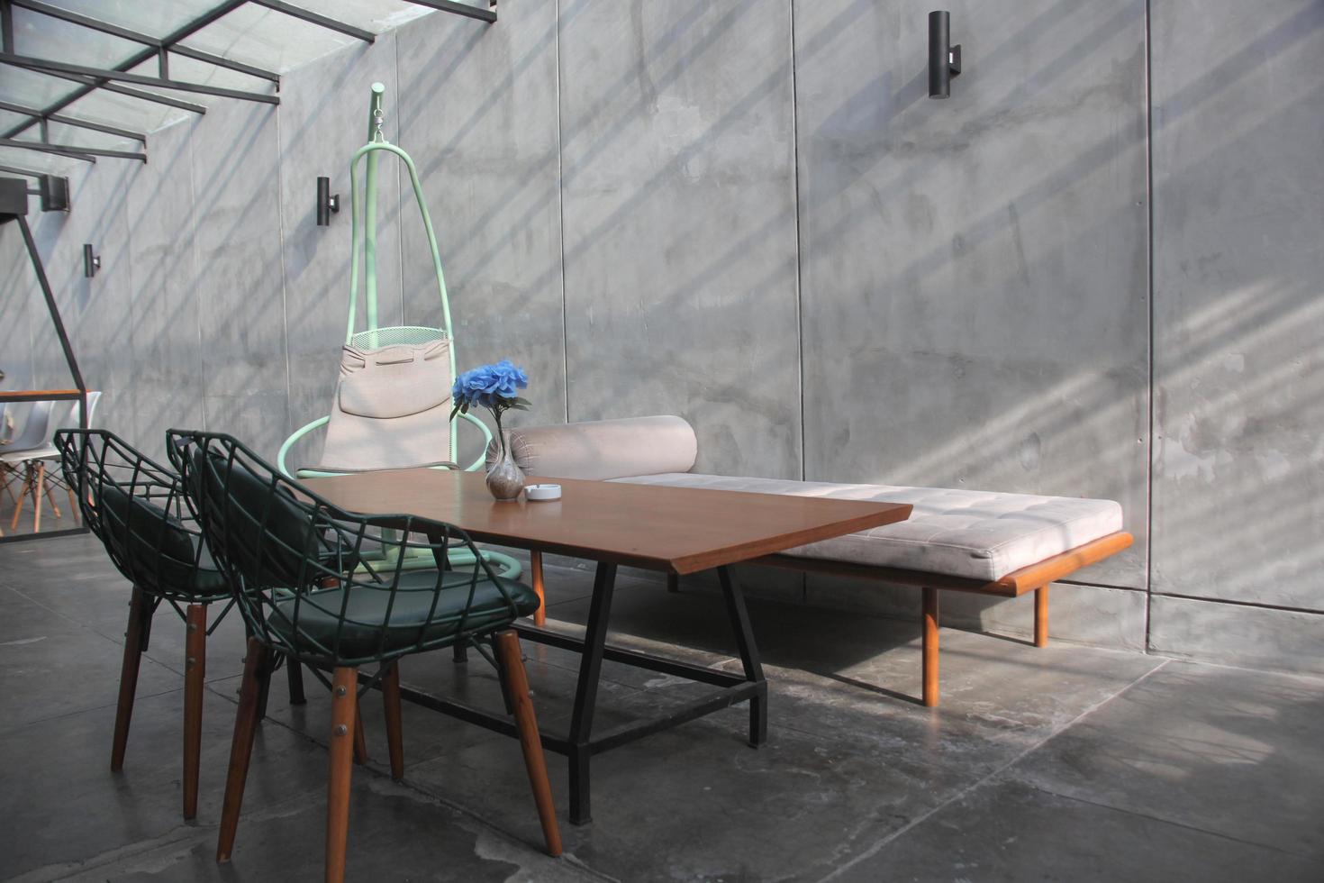 diseño de interiores para habitación familiar con fondo de muro de hormigón, diseño industrial para la vida moderna, juego de muebles, sofá y sillas con mesa y silla colgante de mimbre. bandung, indonesia-, 2022 foto